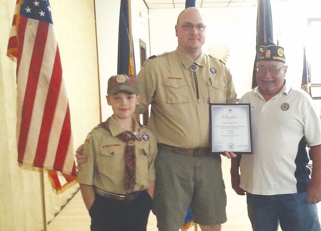Pack 13 Cubmaster Rich Campbell hands American Legion 373 Commander Rudy Freshman the charter document from the Mason Dixon Council. Also in the picture is Webelos Scout Brady Campbell.